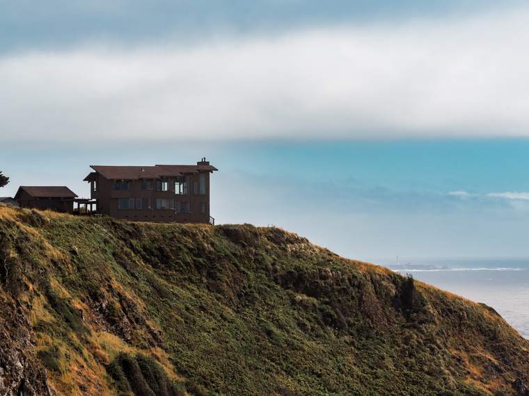A house at the cliff's edge, the sea beyond.